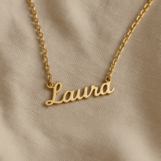 Goldene Namenskette mit personalisiertem Schriftzug auf weichem Leinenstoff